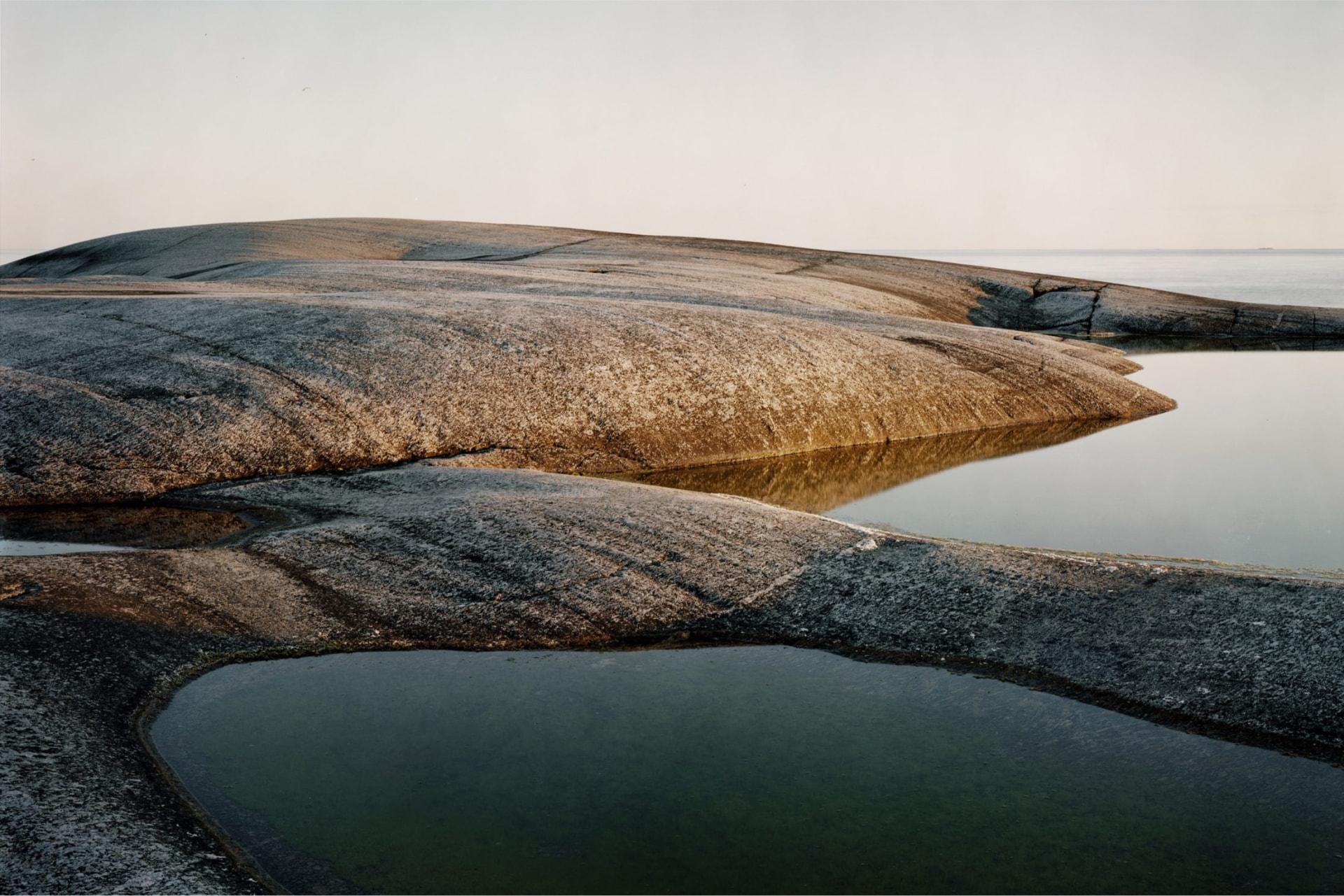 Granite rock and still water on a Nordic shoreline at dawn
